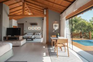 Sala de estar con cama, mesa y piscina en Ponta dos Ganchos Exclusive Resort en Governador Celso Ramos