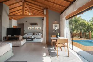 a living room with a bed and a table and a pool at Ponta dos Ganchos Exclusive Resort in Governador Celso Ramos