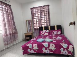 a bedroom with a purple bed with pink flowers on it at Jerai Geopark Cottage 2 bedrooms Pulau Song² in Yan