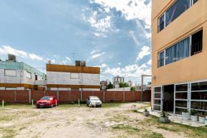 2 voitures garées dans un parking à côté d'un bâtiment dans l'établissement Palmeras Departamentos, à Santa Teresita