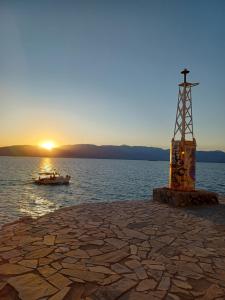 een boot in het water met de zonsondergang op de achtergrond bij Androniki Apartment in Nafplio