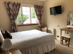 a bedroom with a bed and a television and a window at Distillery Guest House in Fort William