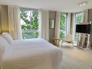 a bedroom with a large white bed and windows at Smart Hotel Montevideo in Montevideo