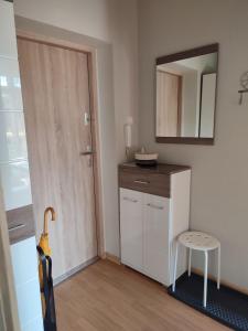 a small white kitchen with a stool and a mirror at Apartament Olivia Centrum z zamknietym parkingiem in Gdańsk