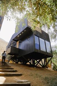 a black house with stairs and a person standing on it at Milodge Elqui Domos in Pisco Elqui