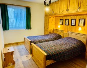 2 łóżka pojedyncze w pokoju z drewnianymi szafkami w obiekcie Sankt Moritz Chesa Ruinatsch 50 w Sankt Moritz