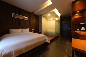 a bedroom with a large white bed and a bathroom at Sejong City Osong Hotel in Cheongju