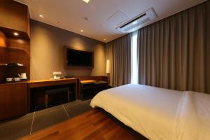 a hotel room with a bed and a desk at Sejong City Osong Hotel in Cheongju