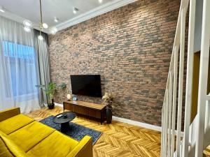 a living room with a brick wall and a television at Olimpia Residence Palace Oradea in Oradea