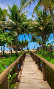 un camino de madera que conduce a la playa con palmeras en Casa próxima do mar com piscina privativa, en Prado