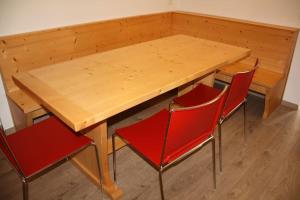 una mesa de madera con 4 sillas rojas alrededor en Appartamento nel Cuore della Val di Sole, en Dimaro