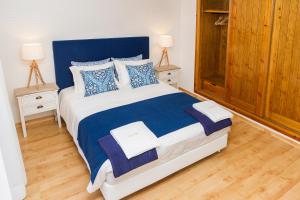 a bedroom with a blue and white bed with two night stands at PIER HOUSES by Nature Bliss in Vila Nova de Milfontes