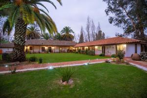 a house with a palm tree and a yard at Hotel Boutique Raíces de Colchagua in Santa Cruz