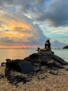 a couple sitting on a rock on the beach at Pani House Hatyai 1 in Hat Yai