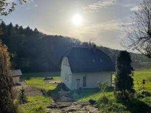 a white house in a field with the sun behind it at Veselka in Dolní Bousov