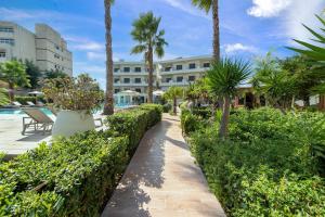 a walkway next to a resort with palm trees at Ixia Dream hotel - Adults only in Ixia