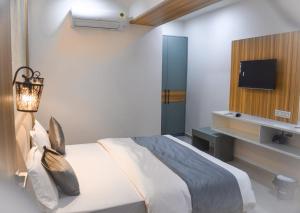 una camera con letto e TV a parete di Hotel The Grand Crystal a Ahmedabad