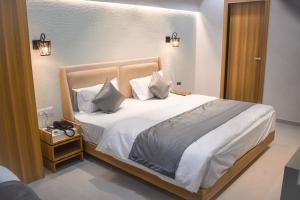 1 dormitorio con 1 cama con sábanas y almohadas blancas en Hotel The Grand Crystal en Ahmedabad