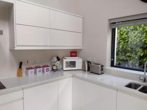 a kitchen with white cabinets and a microwave at Park Avenue in Newcastle