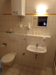 a white bathroom with a toilet and a sink at Hotel Ratscafe Ückeritz in Ueckeritz