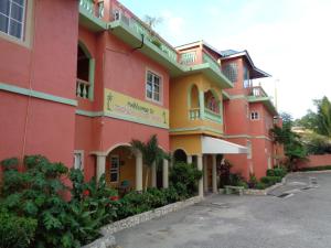 a pink and yellow building with a parking lot at Tropical Court Hotel in Montego Bay