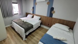 a small bedroom with two beds and a window at Pousada Al Mare in Balneário Camboriú