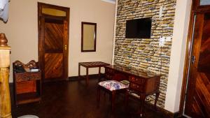 a room with a stone wall with a desk and a television at LUSHOTO EXECUTIVE LODGE in Lushoto