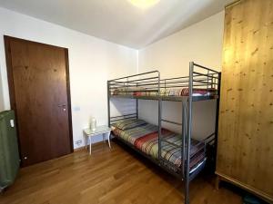 a room with two bunk beds and a door at Pinzolo Centro - Baita Spaziosa con Vista sui Monti in Giustino