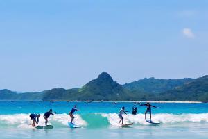 a group of people riding waves on surfboards in the ocean at Zamzam anjani villa in Praya
