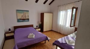a bedroom with two beds with purple sheets and a window at Apartment Lucas in Medulin