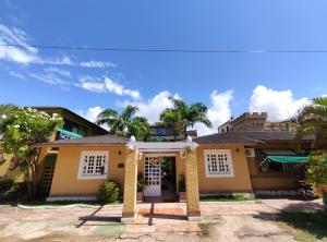 Casa amarilla con puertas blancas y palmeras en Pousada Porto dos Corais, en Maragogi