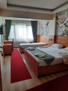 İHVA HOTEL PİERRELOTİ في إسطنبول: غرفة نوم بسريرين وسجادة حمراء