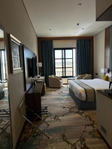 um quarto de hotel com uma cama e uma televisão em Rosa Grand Hotel em Riade