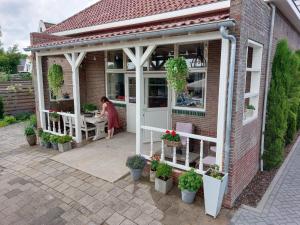a woman sitting at a table outside of a house at BNBSpanbroek in Spanbroek
