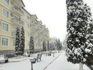 ein schneebedeckter Innenhof eines Gebäudes mit Bäumen und Bänken in der Unterkunft Gabala Hotel in Daşca