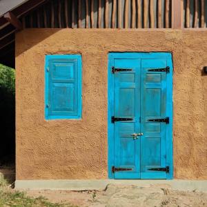 eine blaue Tür und ein Fenster auf der Seite eines Gebäudes in der Unterkunft Yala Lake View Cabanas in Tissamaharama