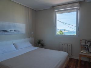 a bedroom with a white bed and a window at "Amaluz Ocean Villa" Bilbao Beach para familias y grupos de amigos in Getxo