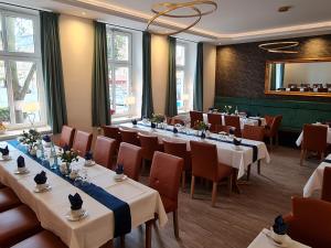 a restaurant with long tables and chairs and windows at Parkhotel Senftenberg in Senftenberg