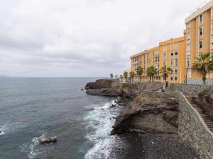 a building on a cliff next to the ocean at MCD Sea Sunset Deluxe in Las Palmas de Gran Canaria