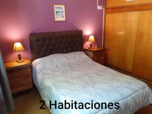 a bedroom with a bed and two night stands with lamps at Cabañas Don Pocho in Villa Cura Brochero