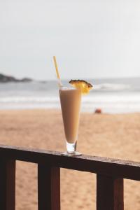 a drink sitting on a railing near the beach at Agonda Sun Set in Agonda