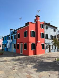 un bâtiment rouge au milieu d'une rue dans l'établissement Alla Torre 735 - Stay Local Burano, à Burano