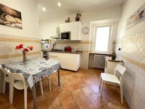 una cocina con mesa y sillas y una cocina con armarios blancos. en Casa Garibaldi 41, en Perugia