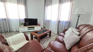 sala de estar con 2 sillas de cuero y TV en Santa Luzia Apt 59 A, en Ribeira Grande