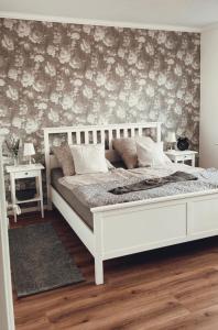 1 dormitorio con cama blanca y papel pintado con motivos florales en Ferienwohnung Ostfriesenherz Emden en Emden