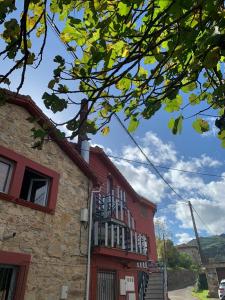un edificio rosso con una porta rossa e un albero di El Desván del Chisco a Cudillero