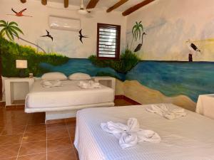 two beds in a room with a painting on the wall at Hotel and Beach Club Escape Holbox in Holbox Island
