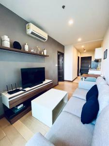 een woonkamer met 2 banken en een flatscreen-tv bij The Astra Condo City Center Chiang Mai in Chiang Mai