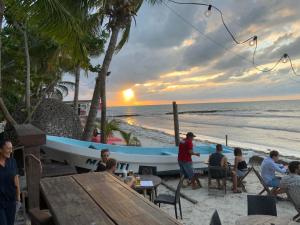 a group of people sitting at tables on the beach with a boat at Hotel and Beach Club Escape Holbox in Holbox Island