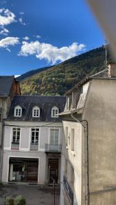 a white building with a mountain in the background at Bel Appartement Bagneres De Luchon Centre in Luchon
